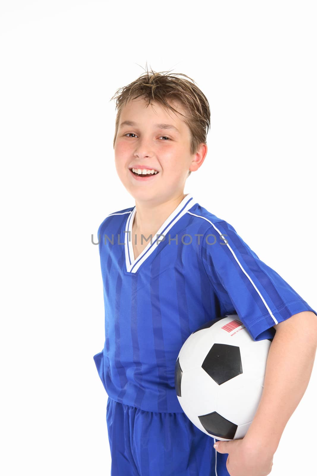 A laughing boy holds a soccer ball under one arm