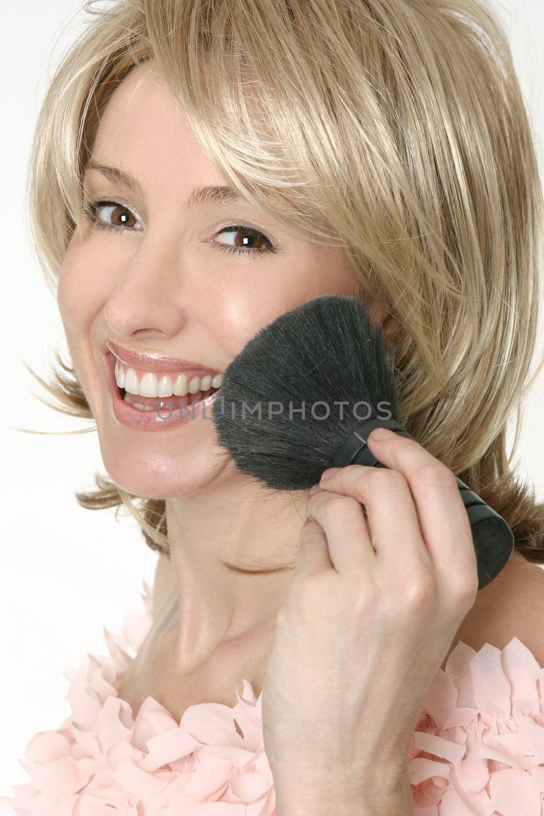 Smiling female holding a large powder brush.