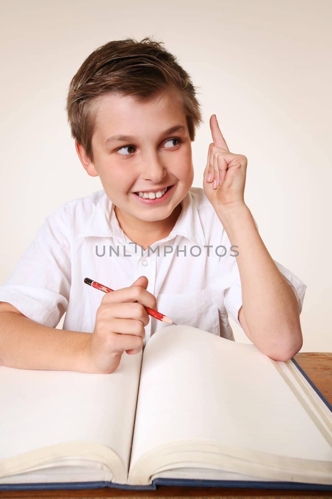 Student school boy sitting at desk with school books has an inspirational idea