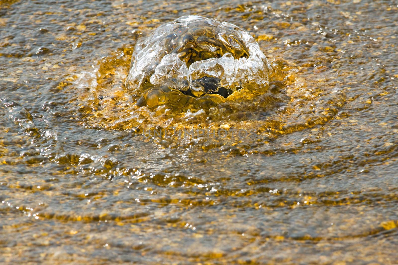 Golden water flowing and  bubbling in summer sunshine - spa and relax concept