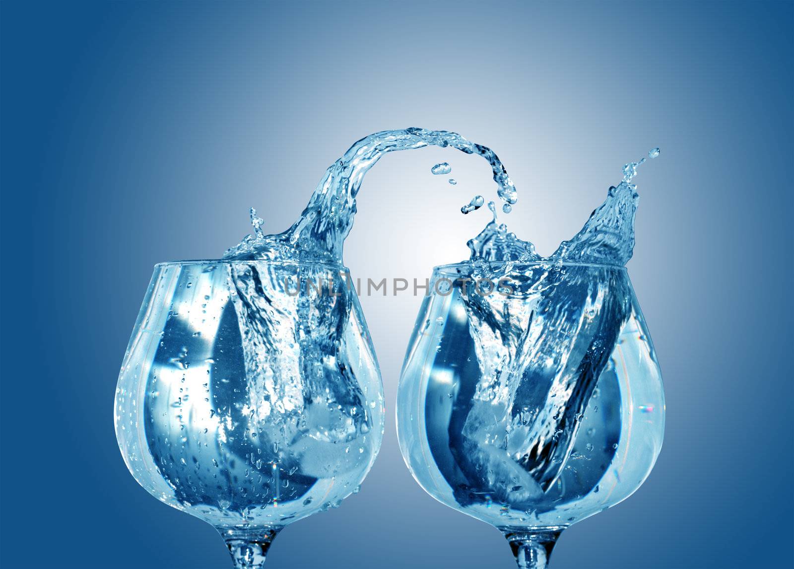 Two nice goblets with cold splashihg water on blue background. Isolated with clipping path