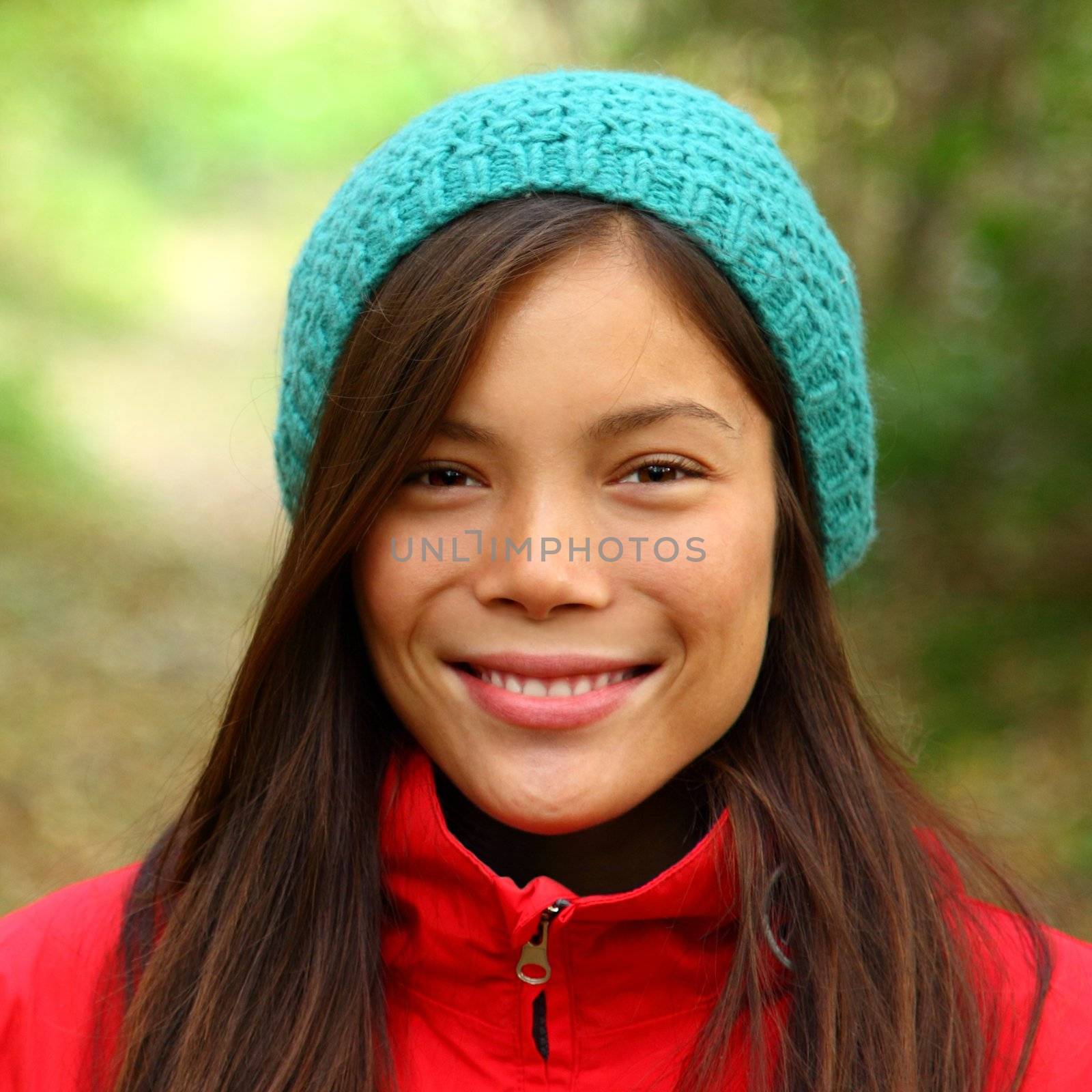 Woman smiling outdoors in Autumn. Beautiful mixed asian / caucasian woman walking in the forest on a fall day.