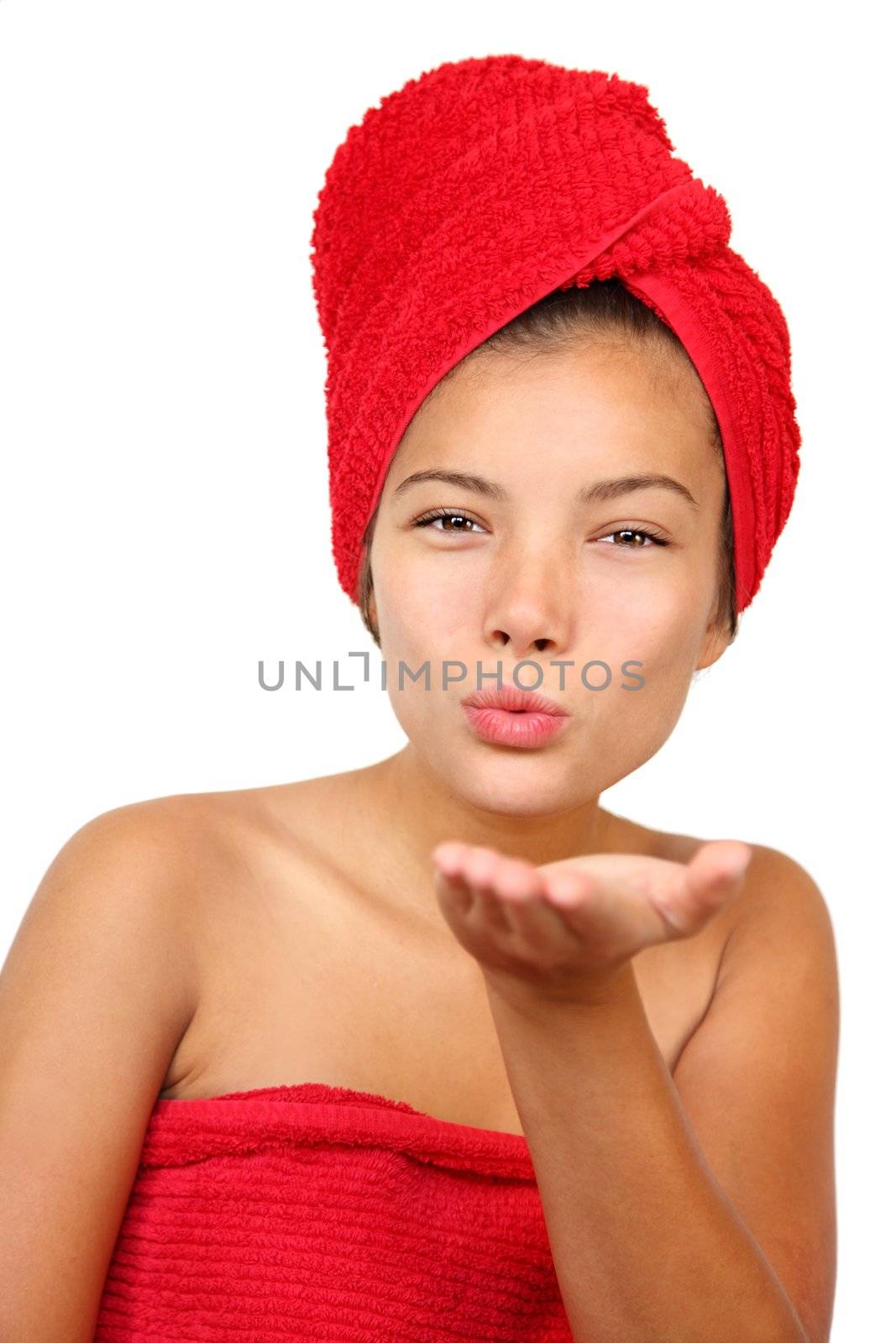 Woman blowing a finger kiss at the camera. Just out of the shower holding towel. Beautiful young mixed race asian / caucasian woman model. 
