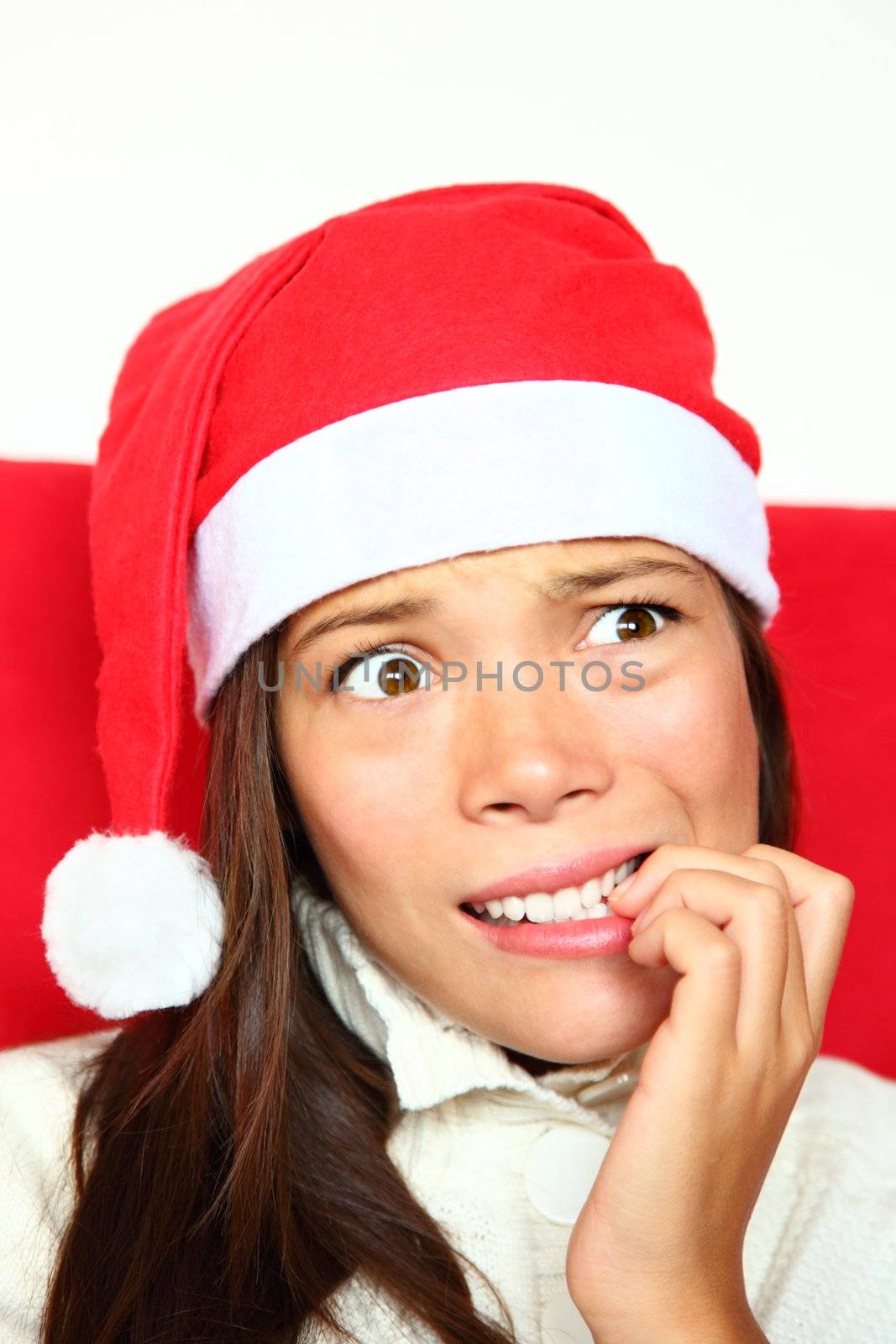 Christmas woman with santa hat nervous biting nails. Beautiful mixed asian / caucasian model. 