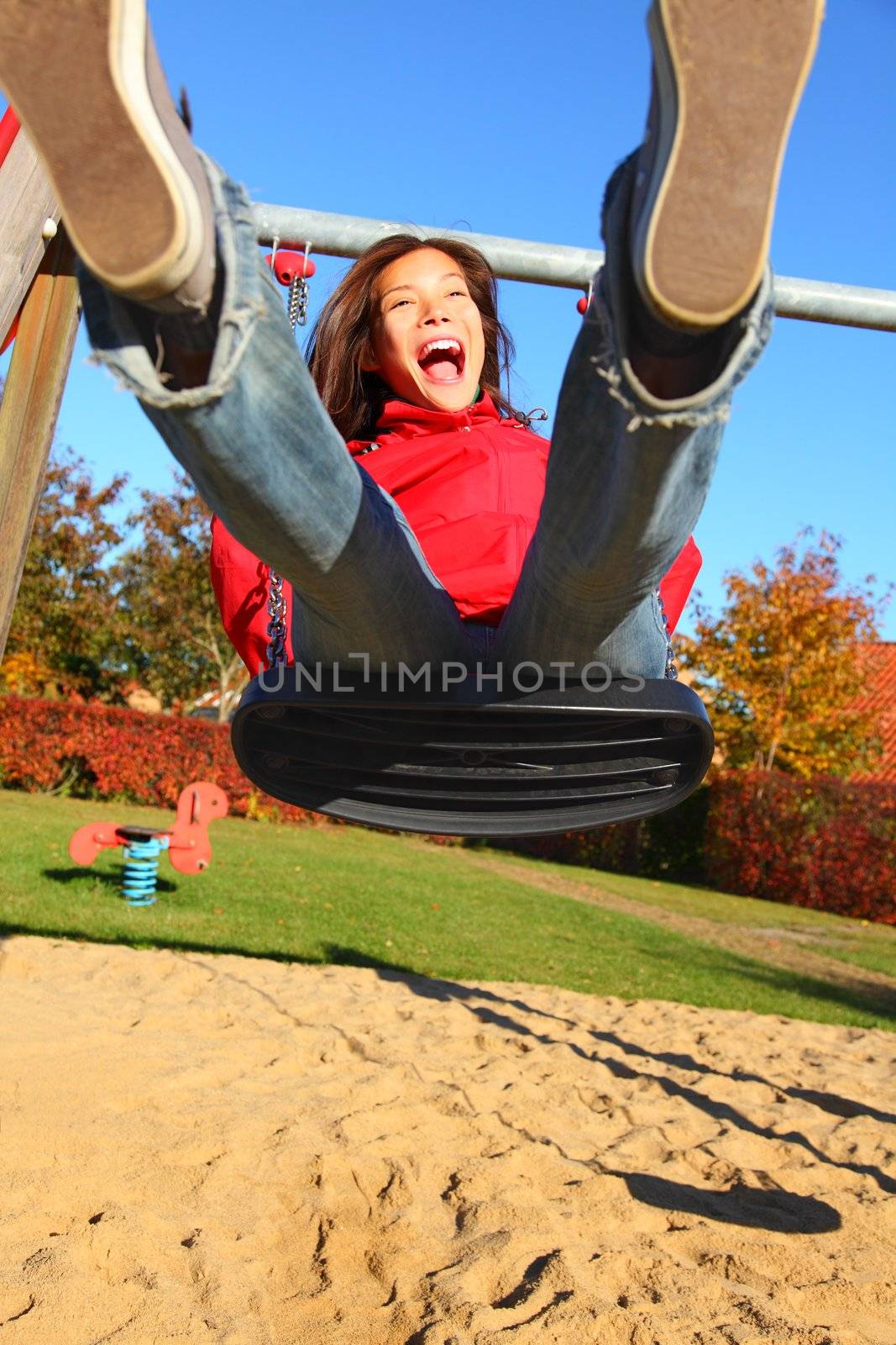 Swing. Happy young woman swinging on a playground.