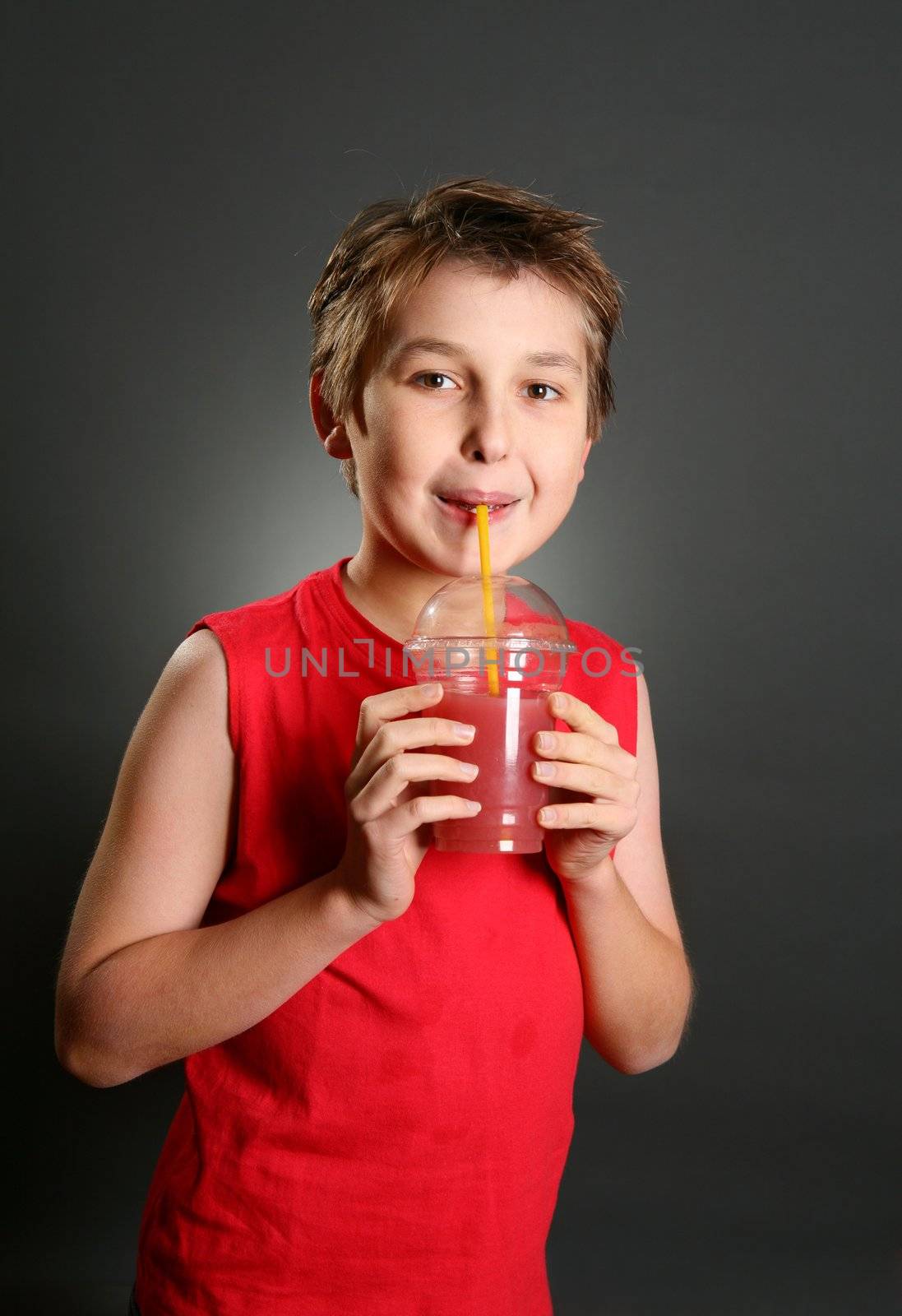 A young boy holds a fresh berry juice in a clear plastic takeaway container
