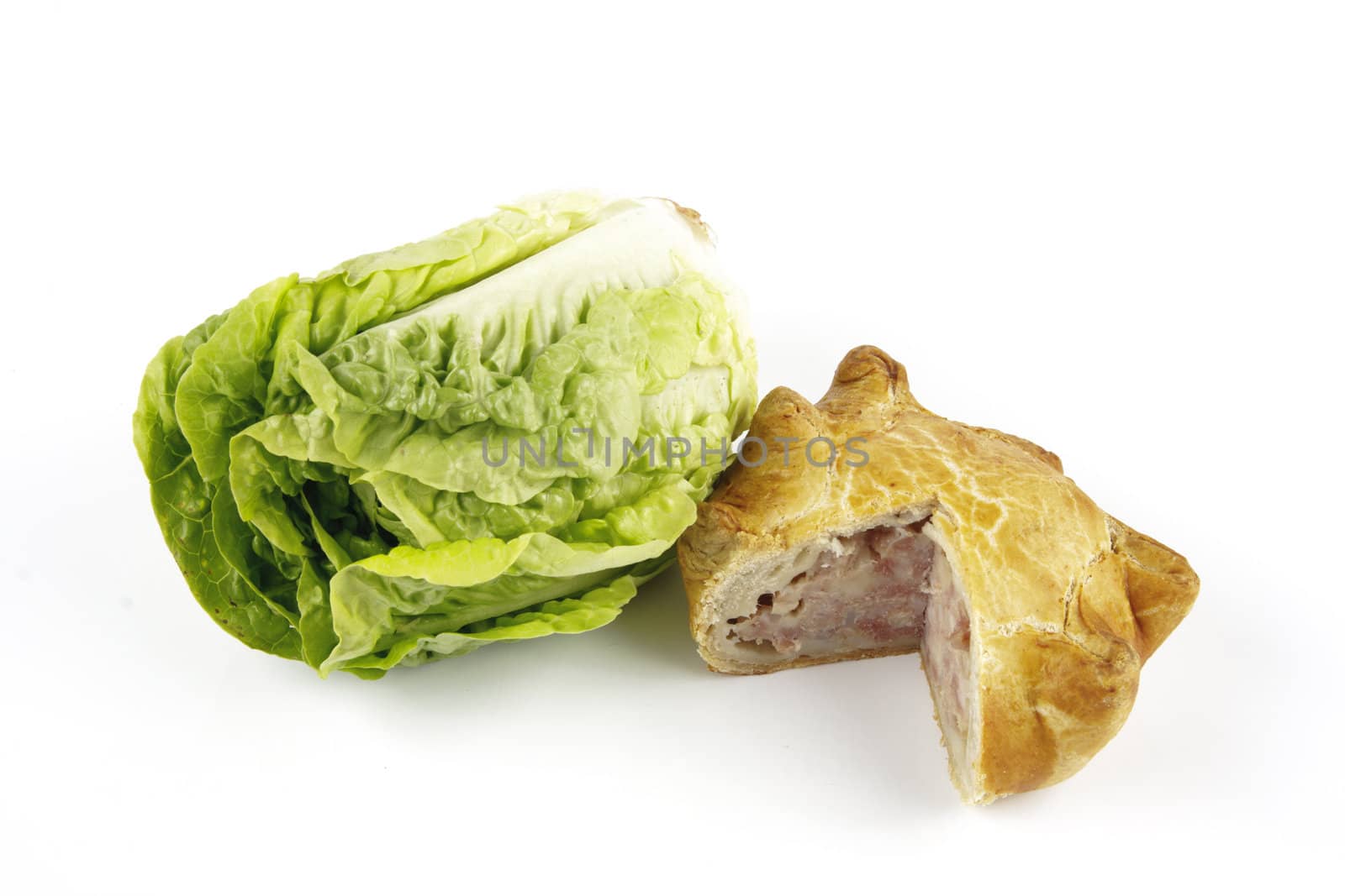Contradiction between healthy food and junk food using a green salad lettace and pork pie on a reflective white background 