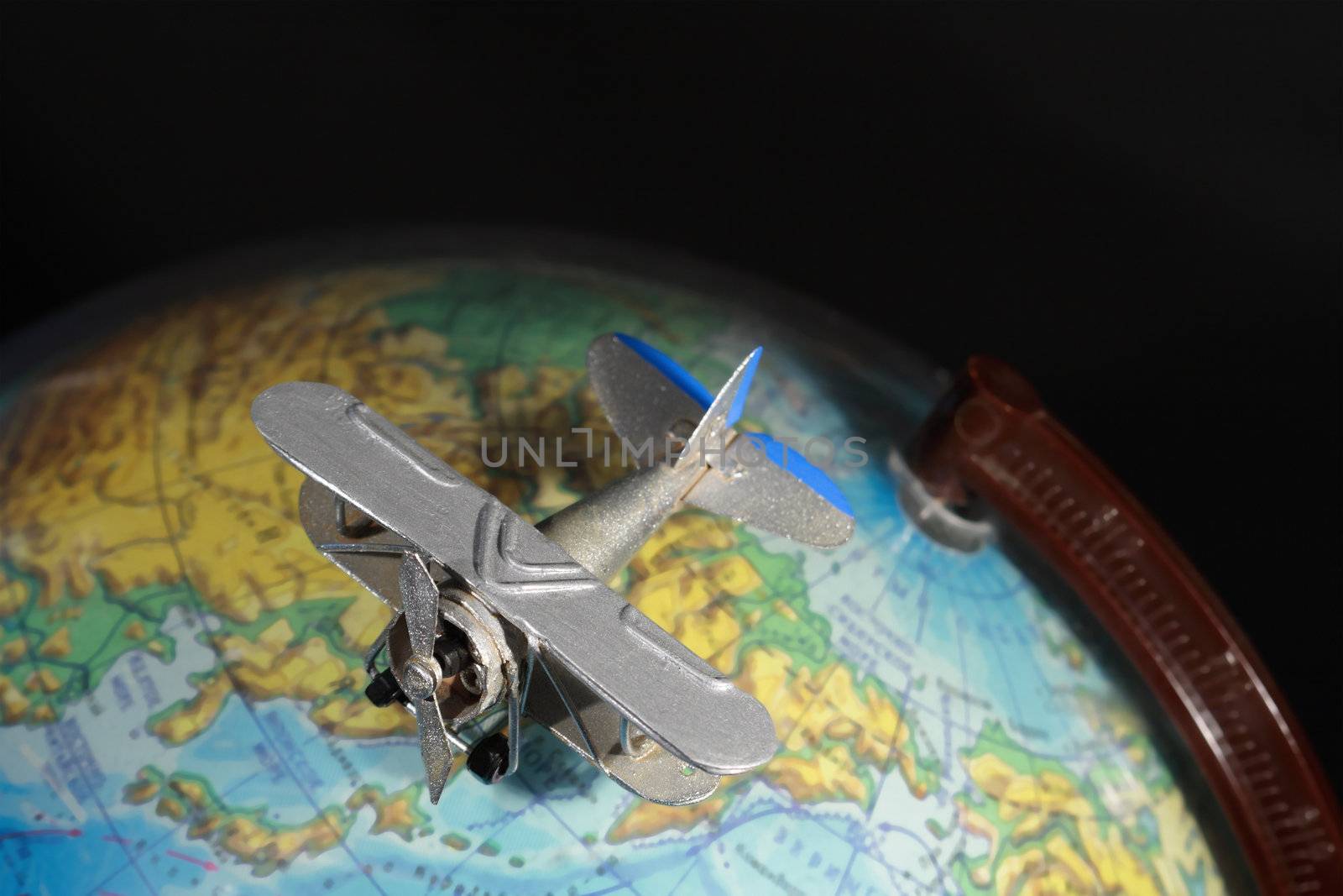 Miniature model of vintage biplane on big color globe