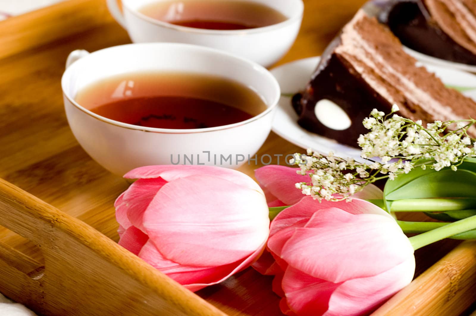 Breakfast tray on bed with tea, cakes and tulips