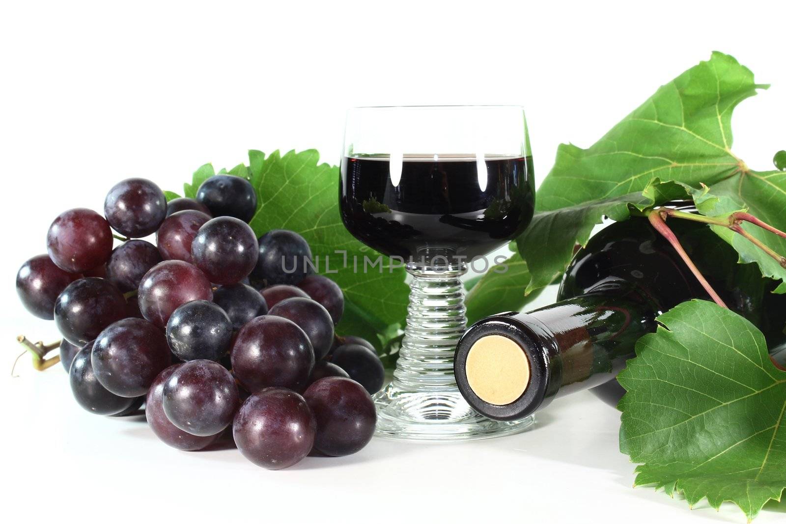 a bottle of red wine and fresh grapes on a white background