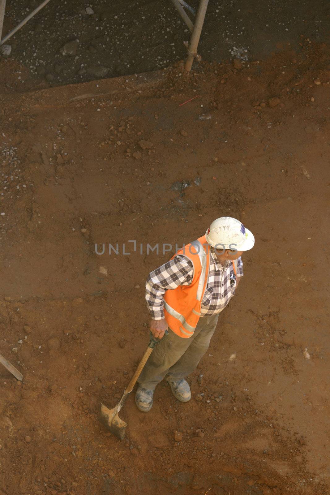 A workman leans on his shovel in a dirt pit
