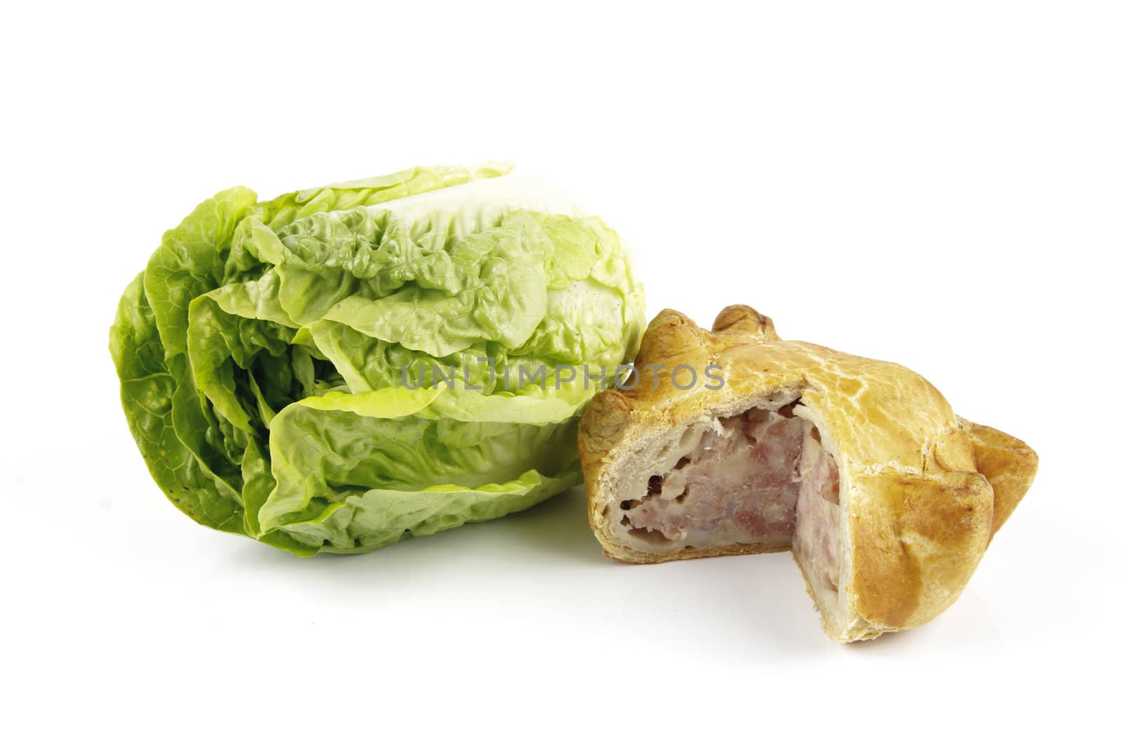 Contradiction between healthy food and junk food using a green salad lettace and pork pie on a reflective white background 