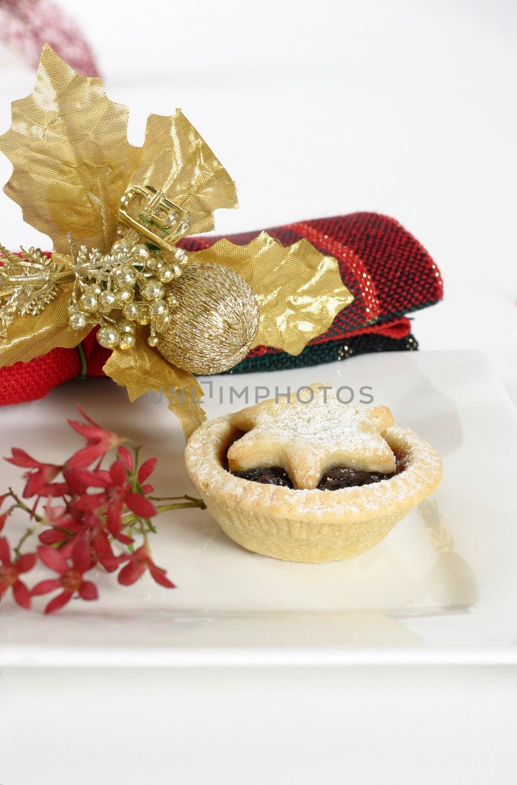 Fruit mince pie on a plate adorned with Australian Christmas bush and napkin.