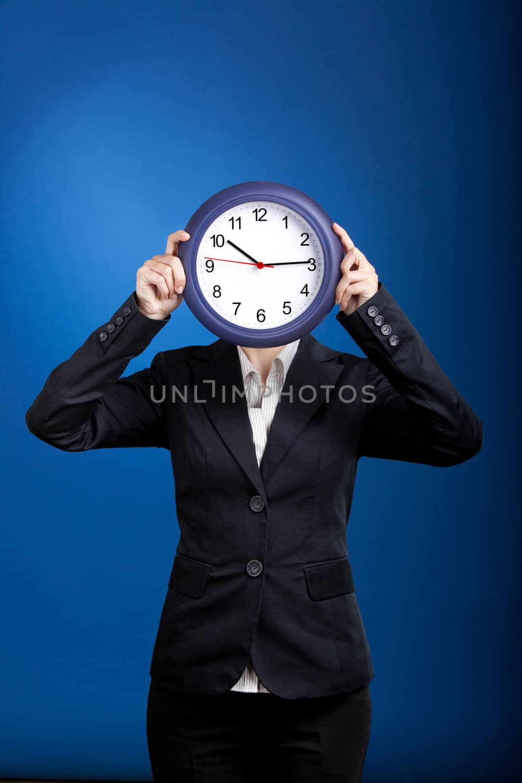 Beautiful young business woman olding a clock over a blue background