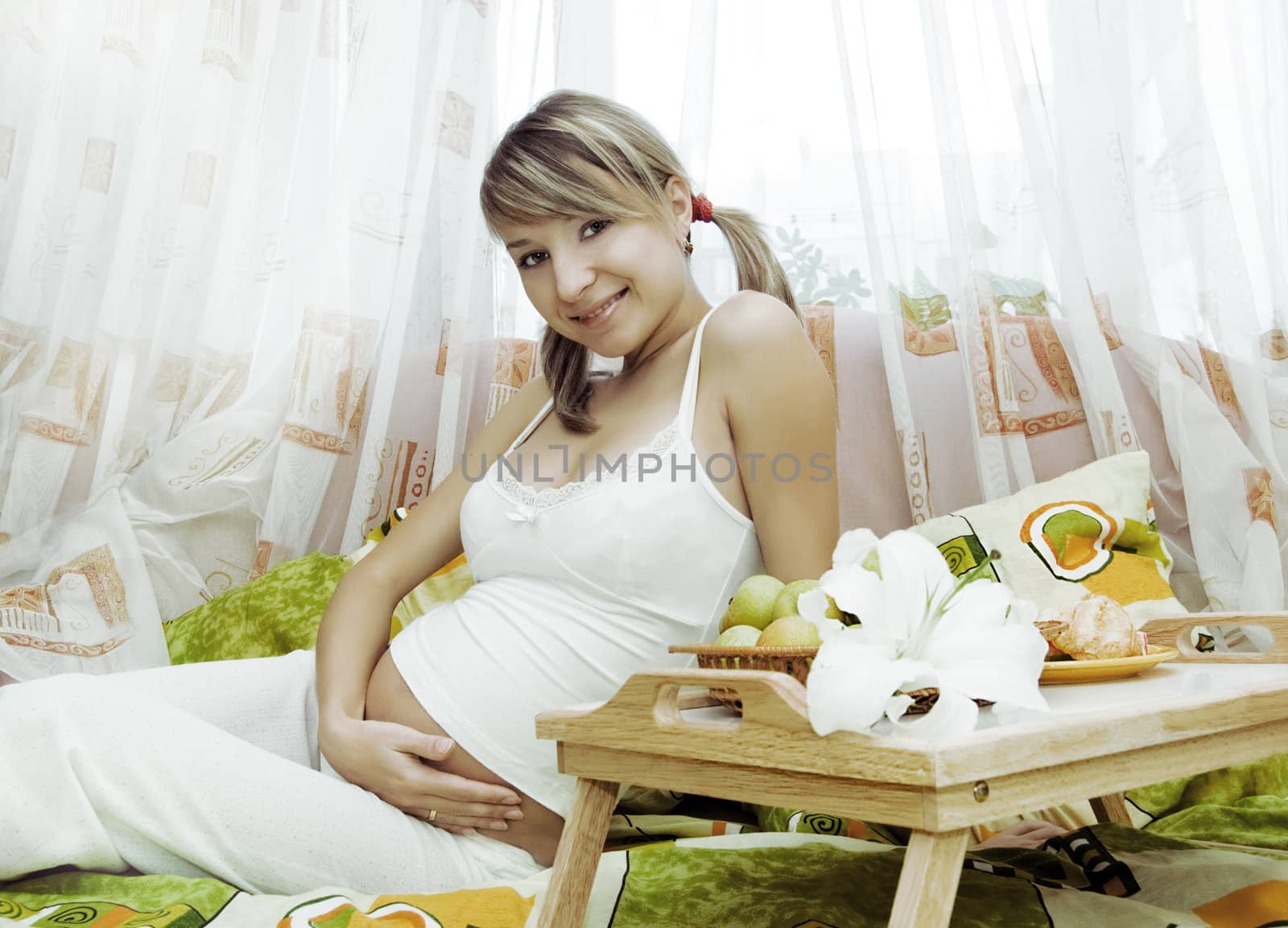 Pretty pregnant woman having breakfast in bed
