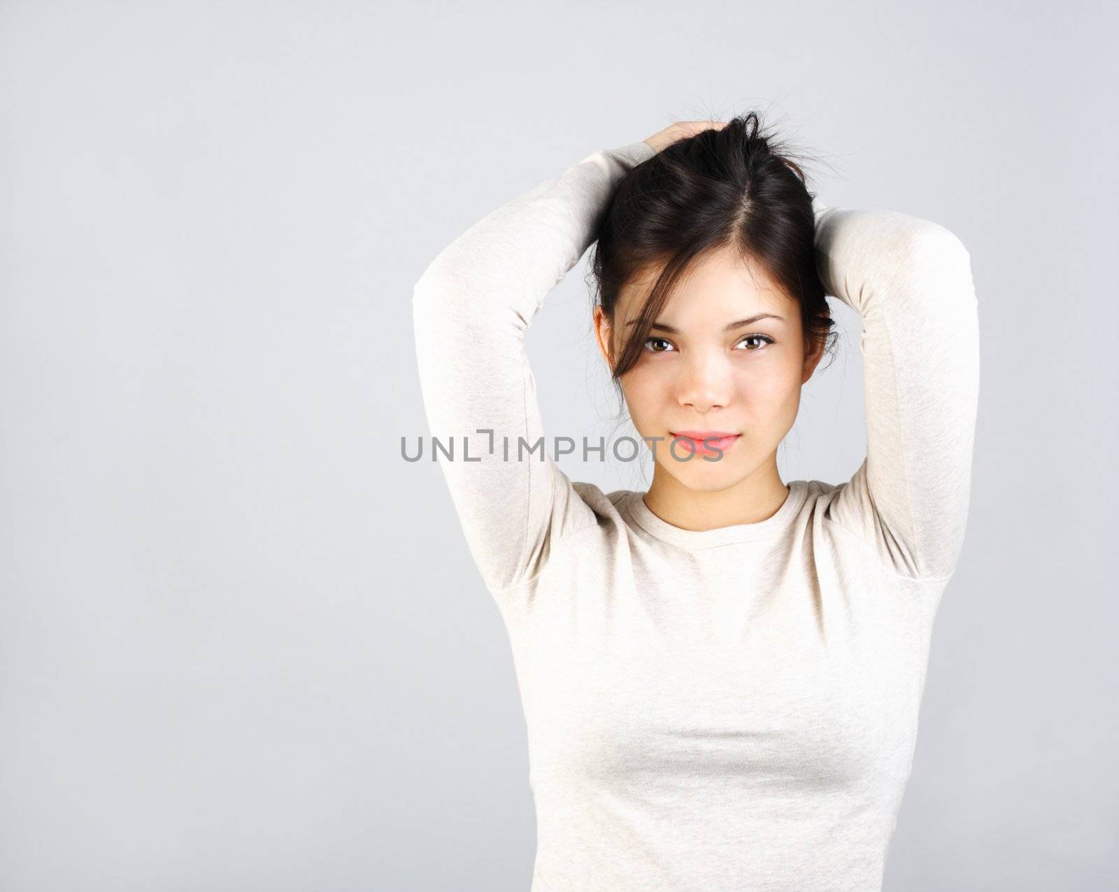 Natural looking asian girl shy and serious posing on gray background.