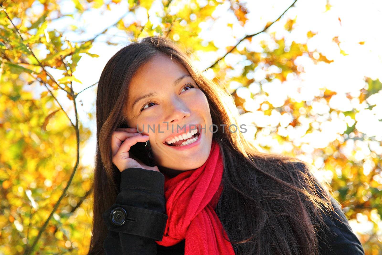 Happy woman on cellphone outside in park. Beautiful mixed race caucasian / asian woman,