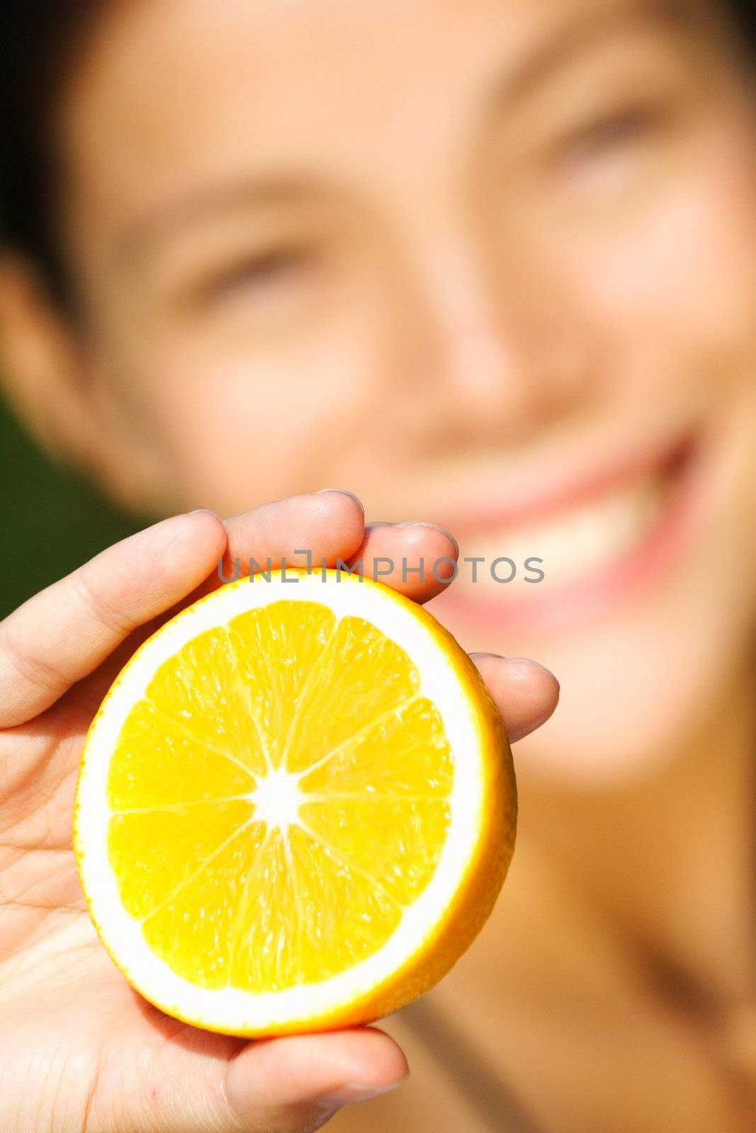 Health and orange concept. Asian woman smiling showing an orange.