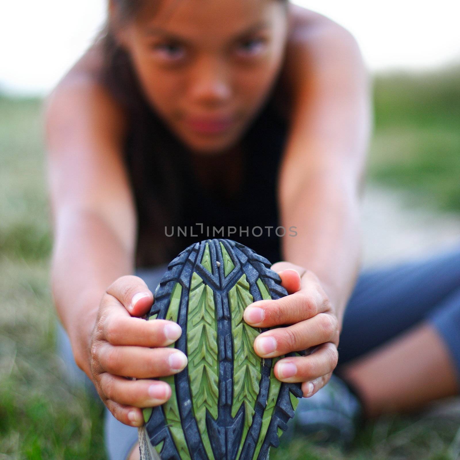 Woman stretching out during outdoor exercise in the fall. Shallow depth of field, focus on shoe.