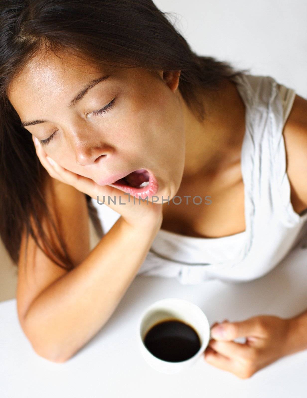 young woman drinking coffee in early morning, yawning and tired.