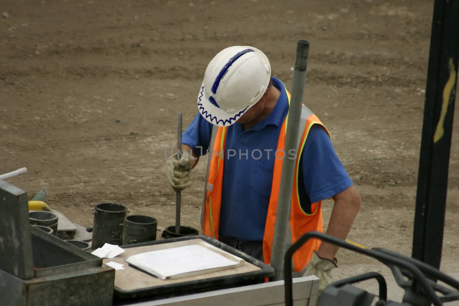 a man stomps concrete into moulds on a construction site according to plans. Focus on head.  Some movement
