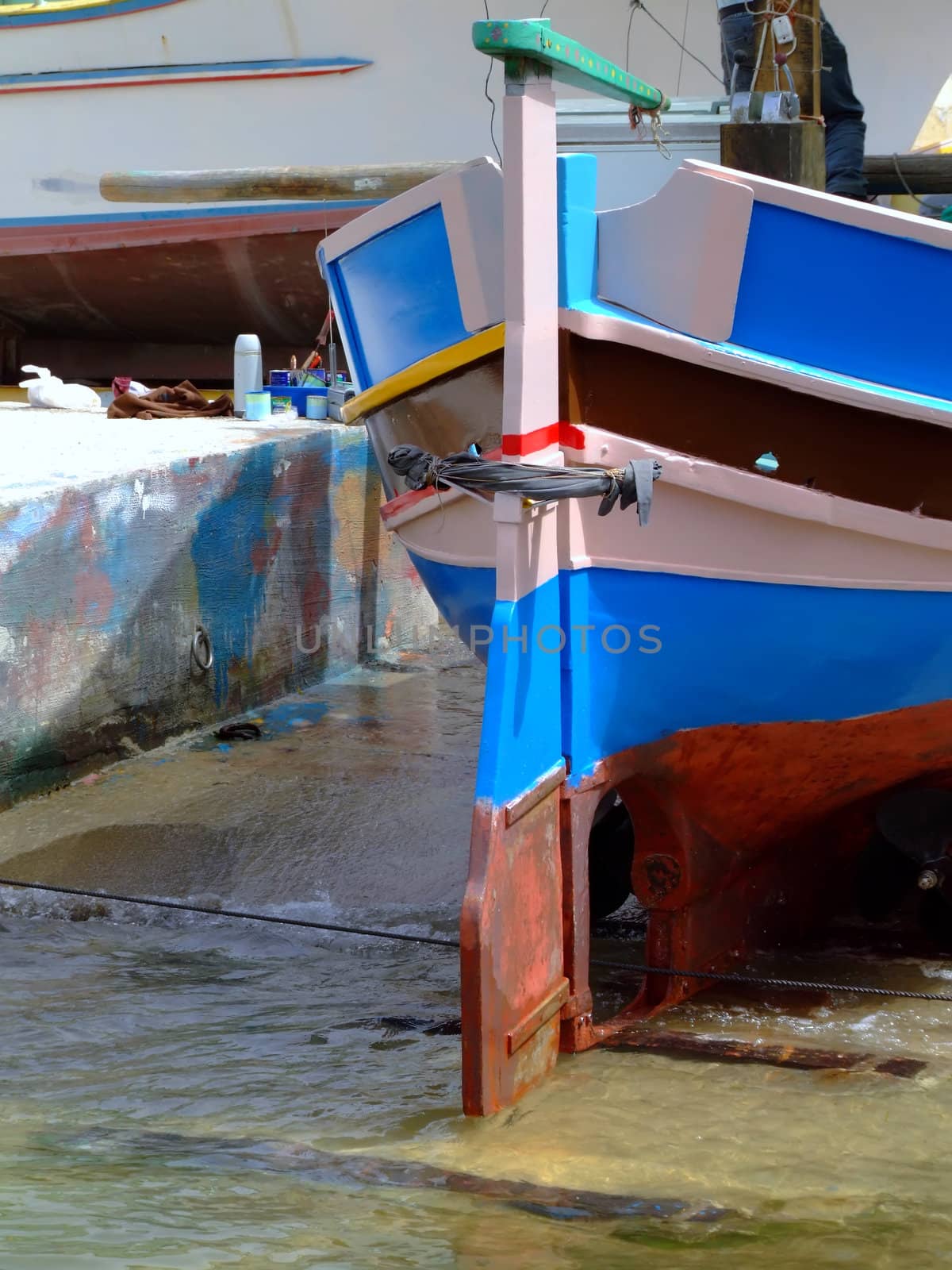 Traditional colors of the traditional Malta fishing boats, commonly known as luzzu or dghajsa. This boat being repaired on quayside, and painted