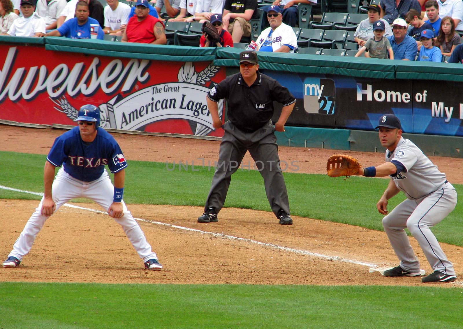A view of the first base runner, first baseman and umpire at a professional baseball game.
