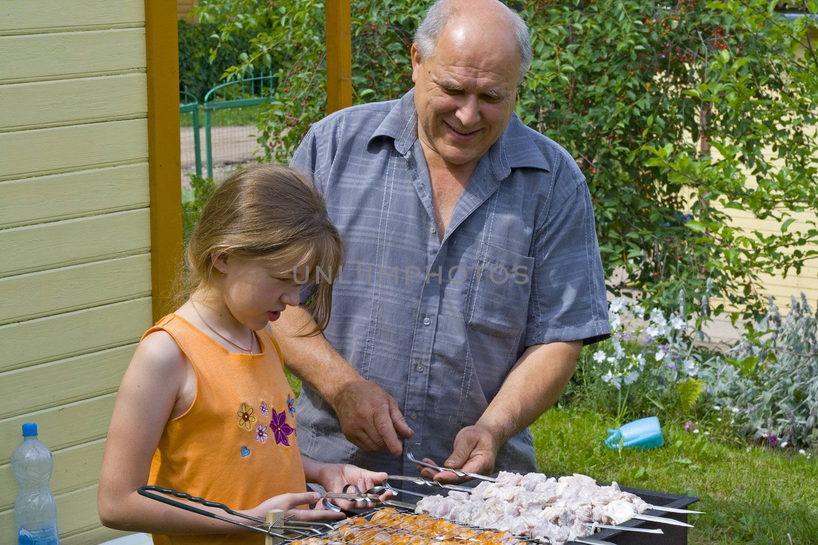 The grandfather learns the granddaughter to do a kebab