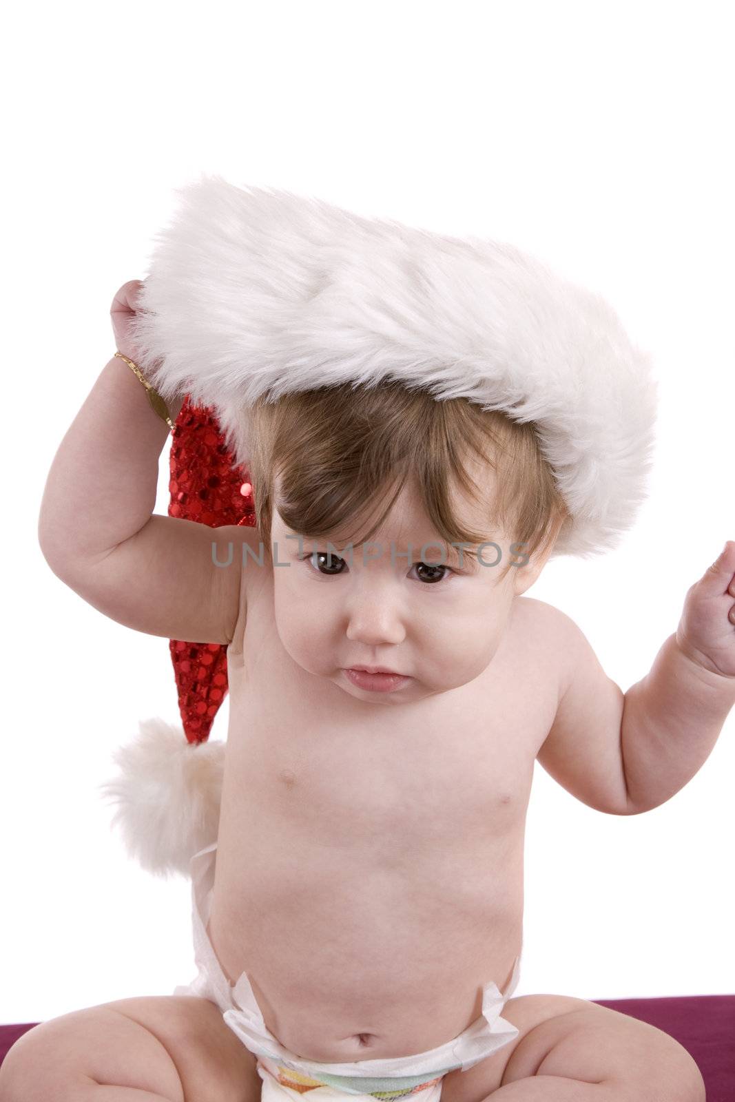 Baby clearly being annoyed with a christmas hat and pulling it of