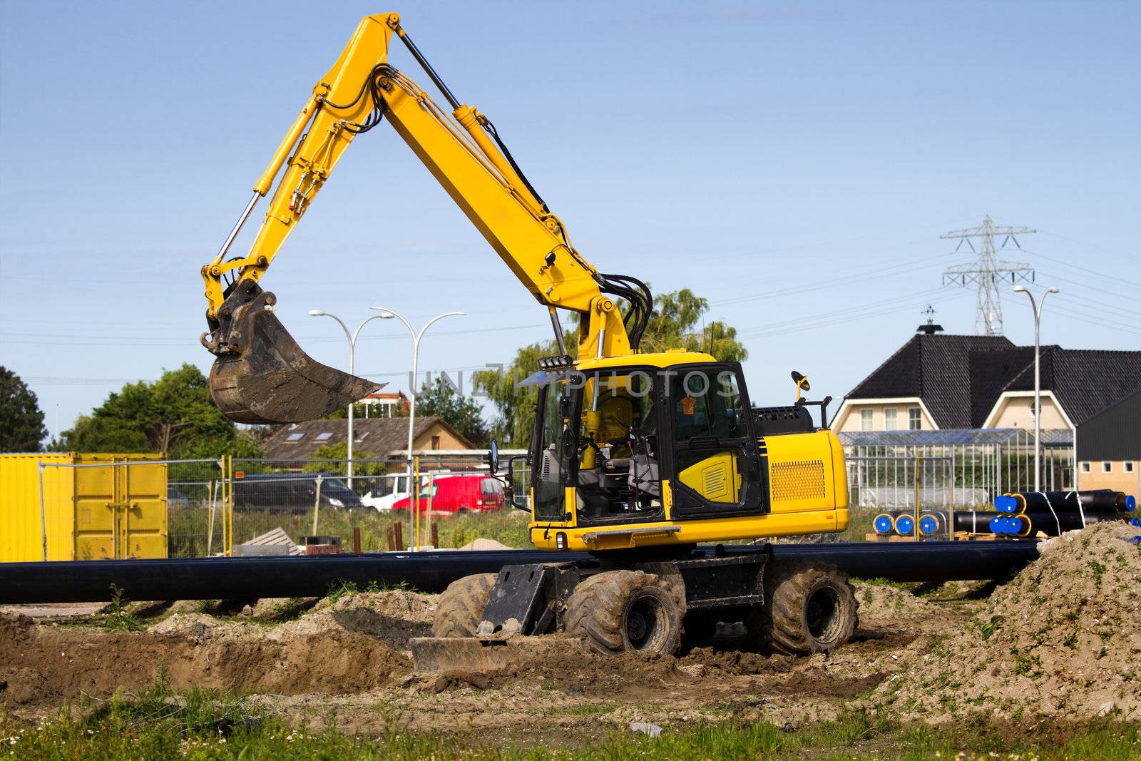 Excavator at work digging up ground for new to build houses - horizontal