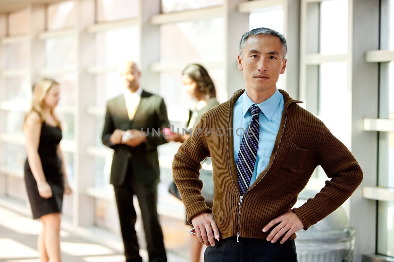 A cansual Asian looking business man with colleagues in the background
