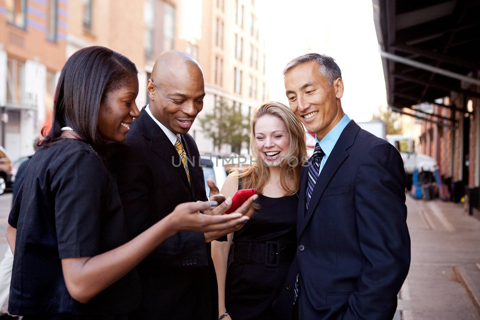A group of business people looking at a cell phone and laughing