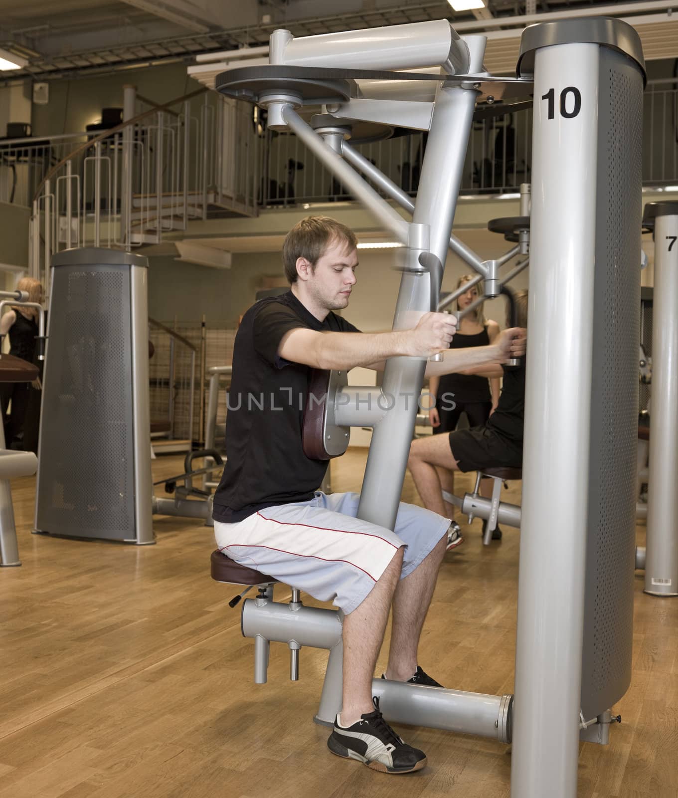 Young man using an exercise machine  by gemenacom