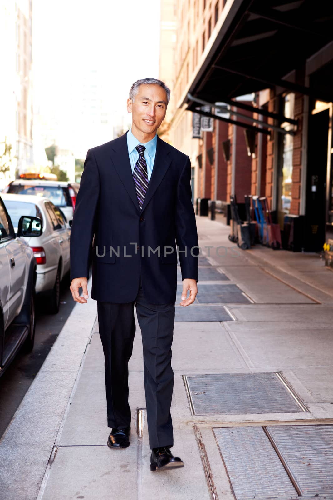 An asian looking business man walking in a street