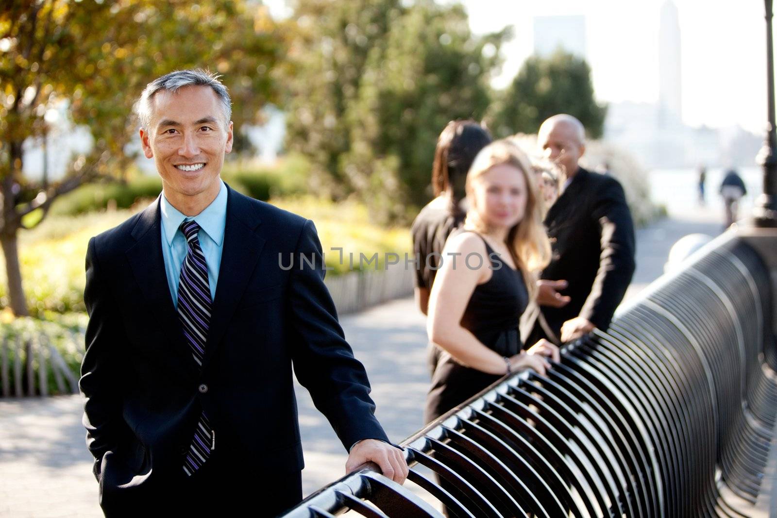 A group of business people outside - sharp focus on Asian man in foreground