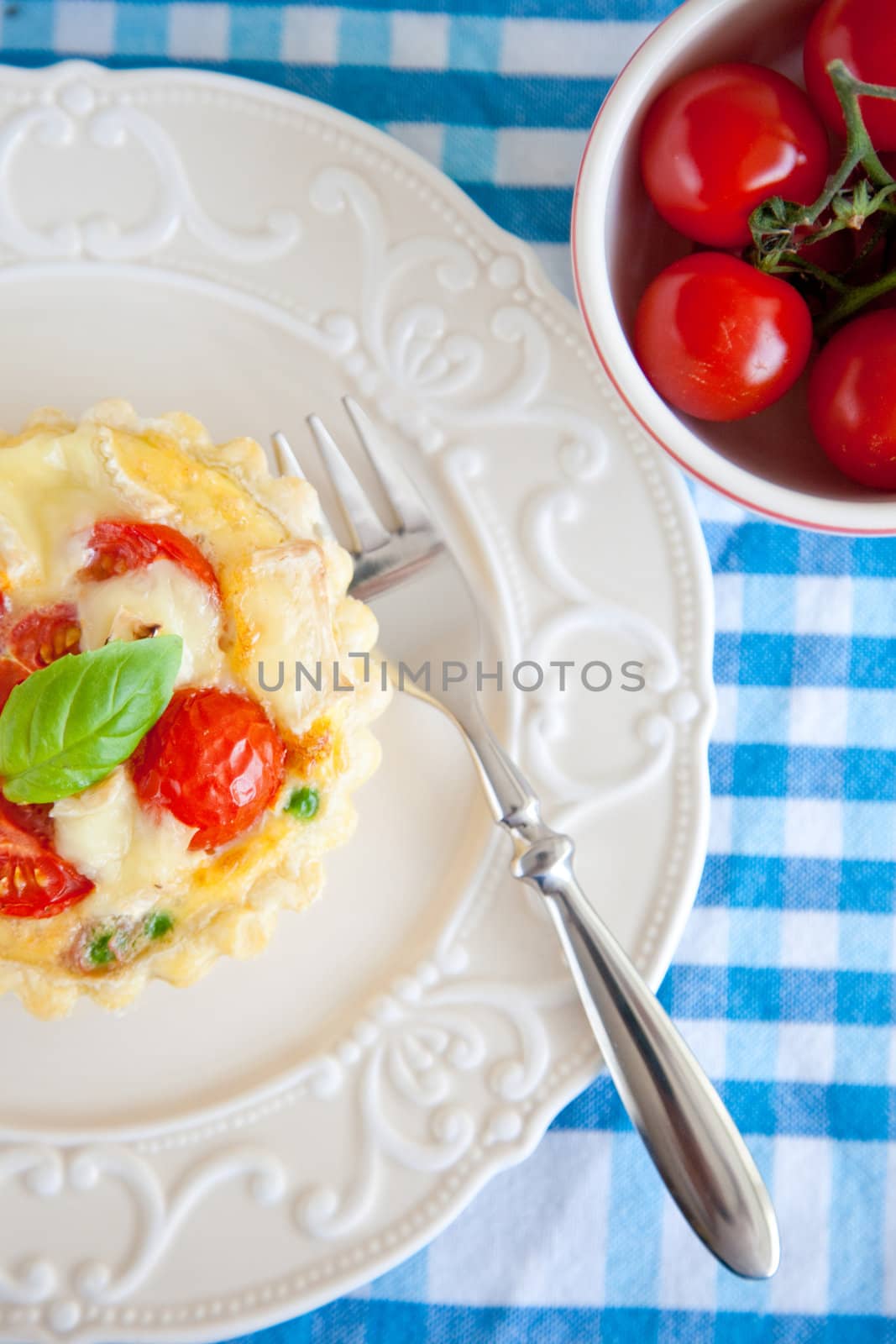 Small puff pastry pie with cherry tomatoes, brie, peas and basil