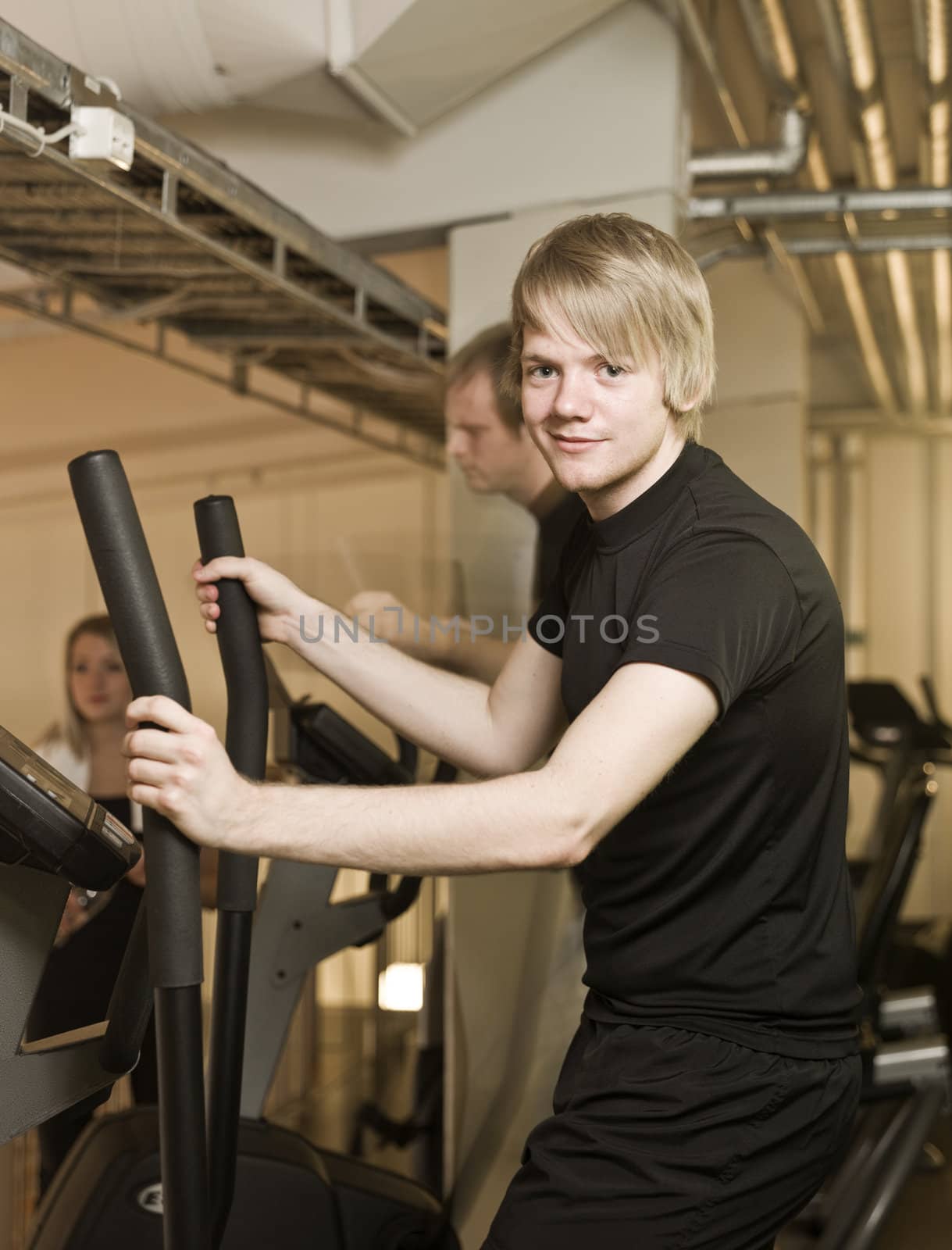 Young man looking into the camera while using an exercise machine