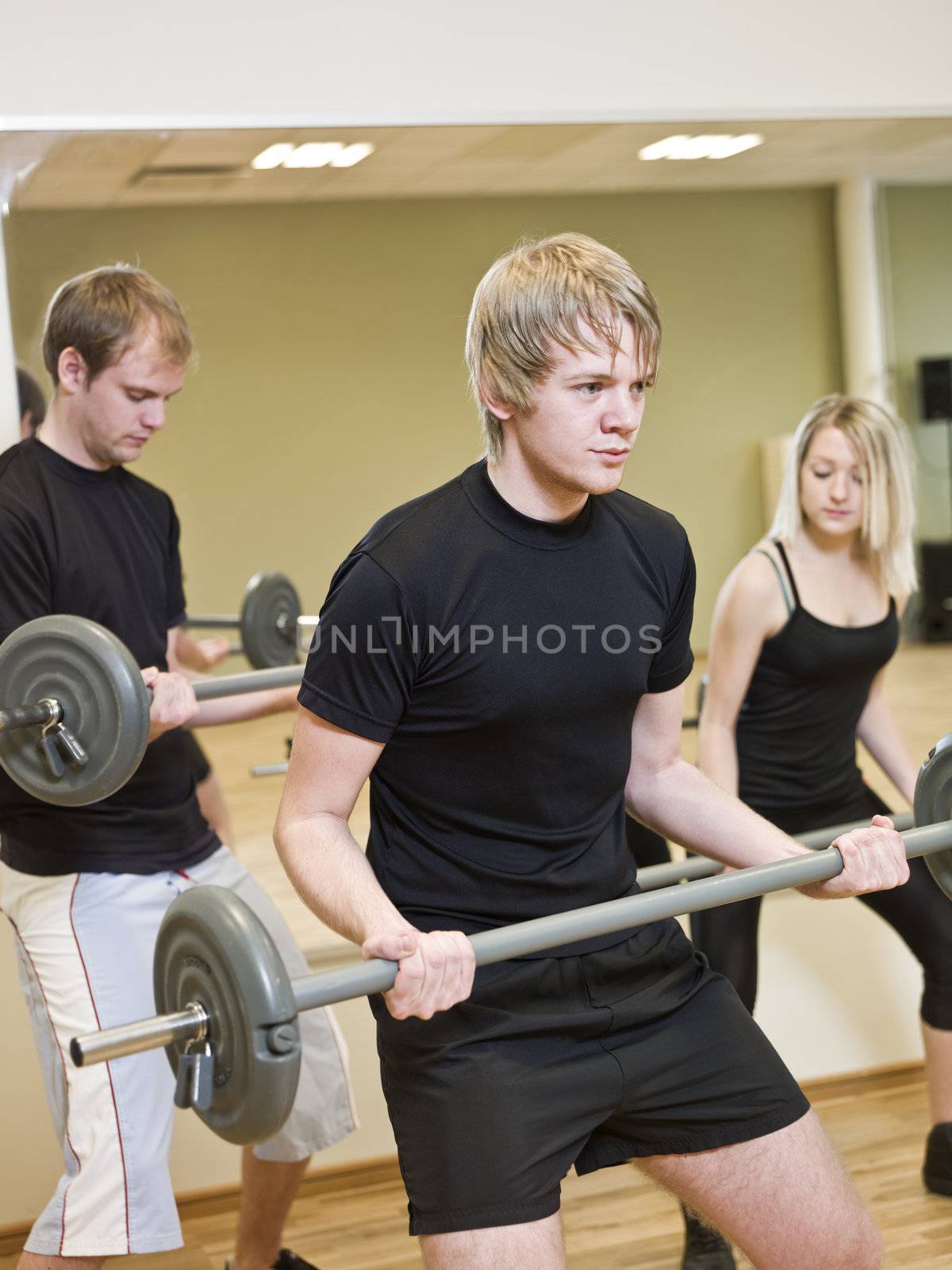 Group of people lifting weights with a young man in focus