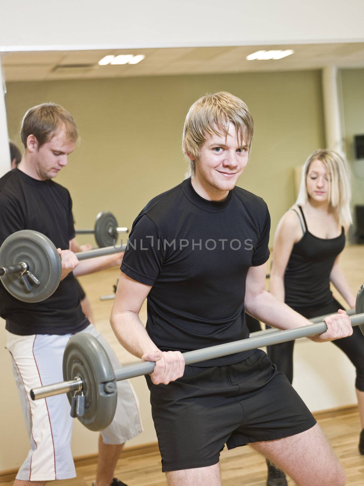 Group of people lifting weights with a young man in focus