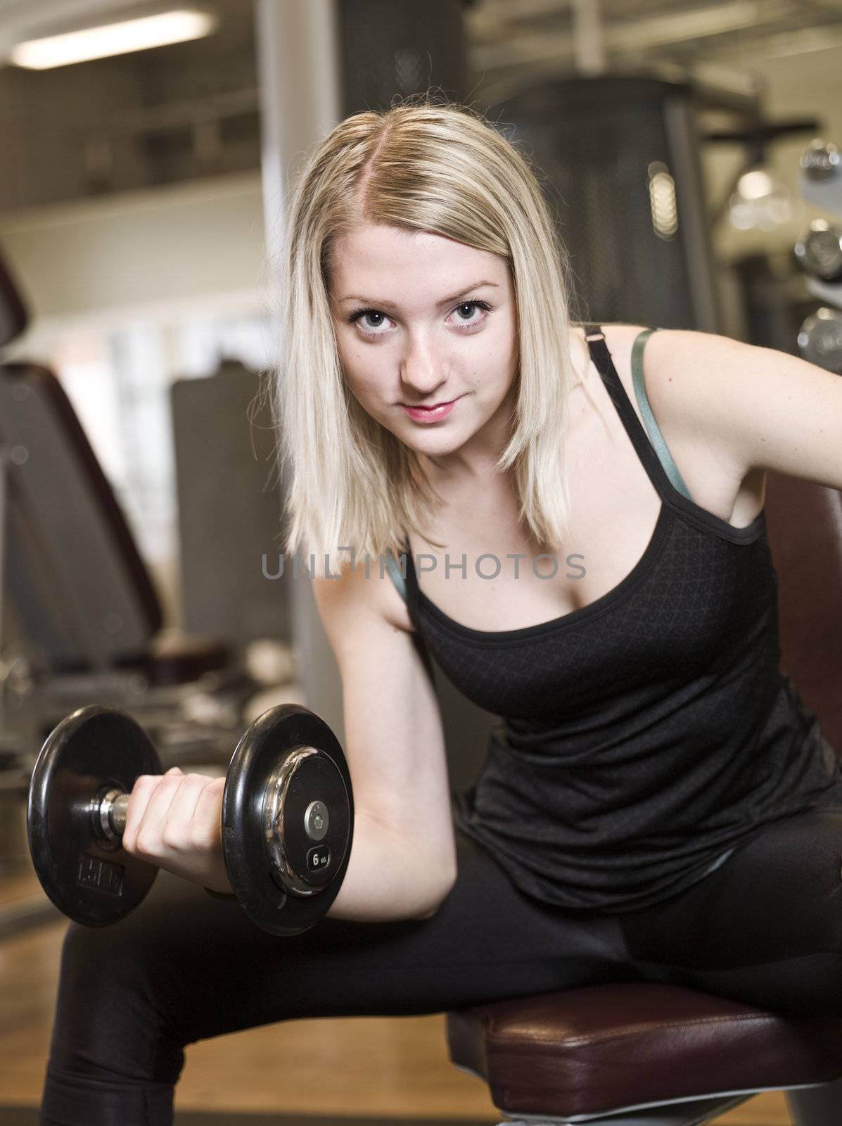 Young woman lifting weights by gemenacom