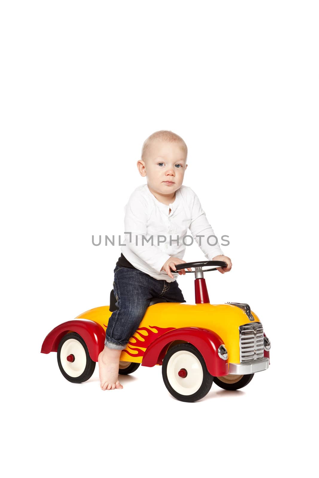 Boy riding his toycar isolated against white