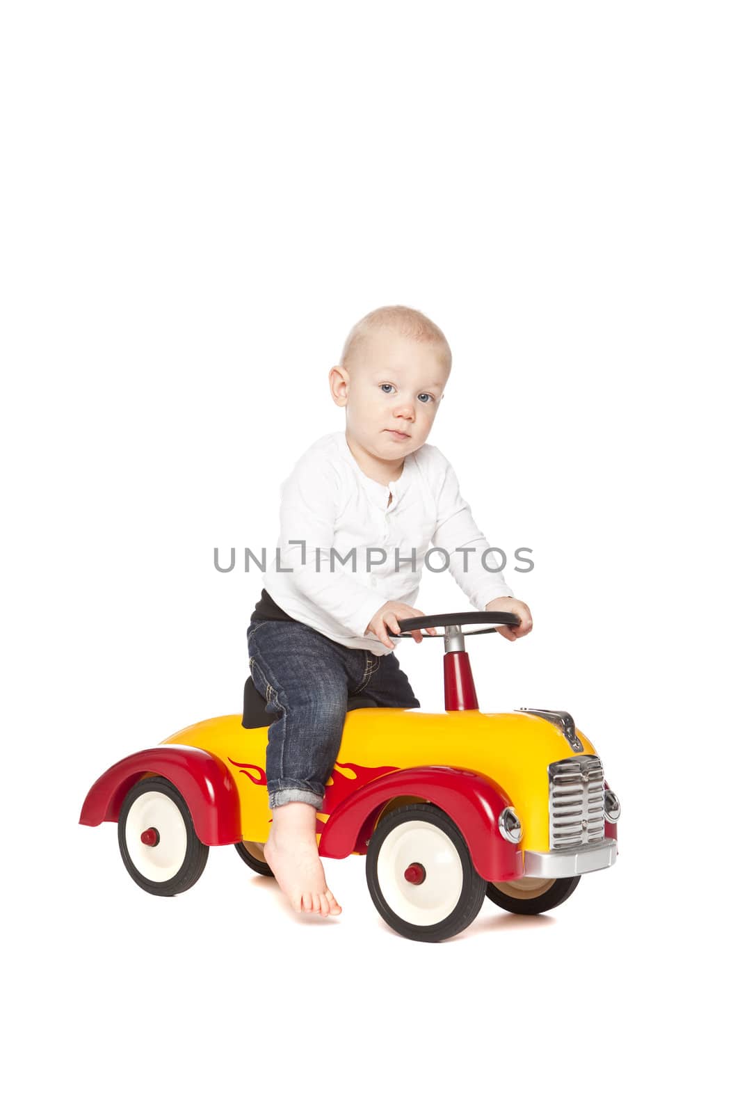 Boy riding his toycar isolated against white