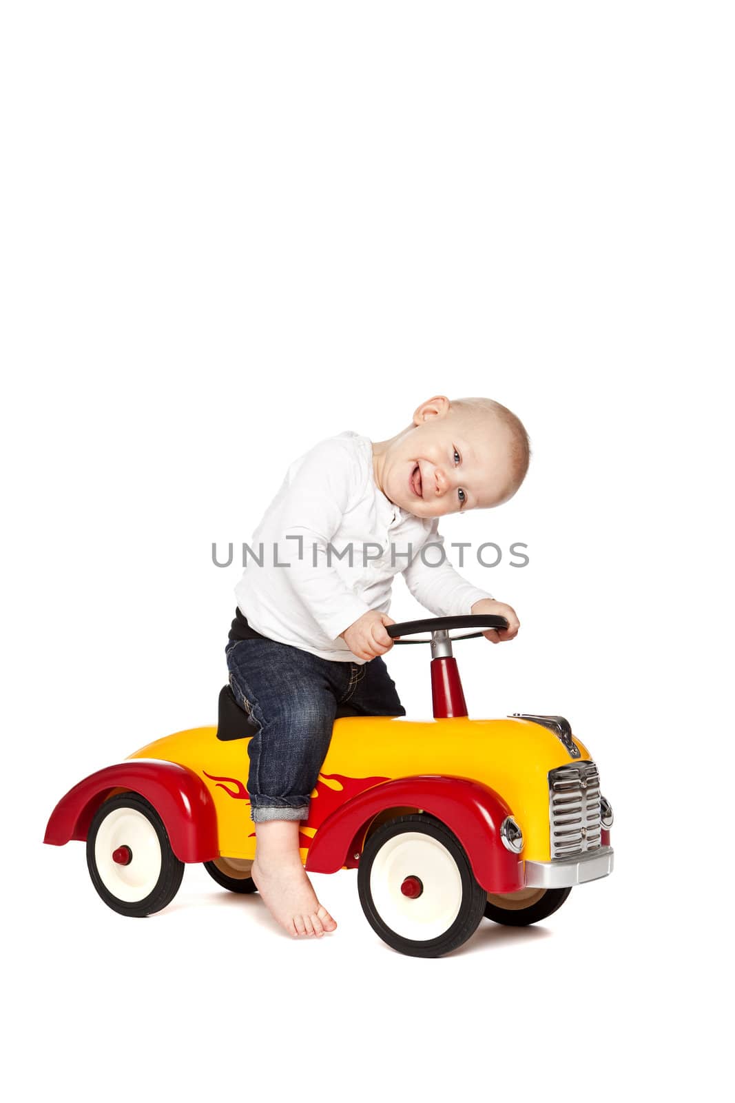 Boy riding his toycar isolated against white