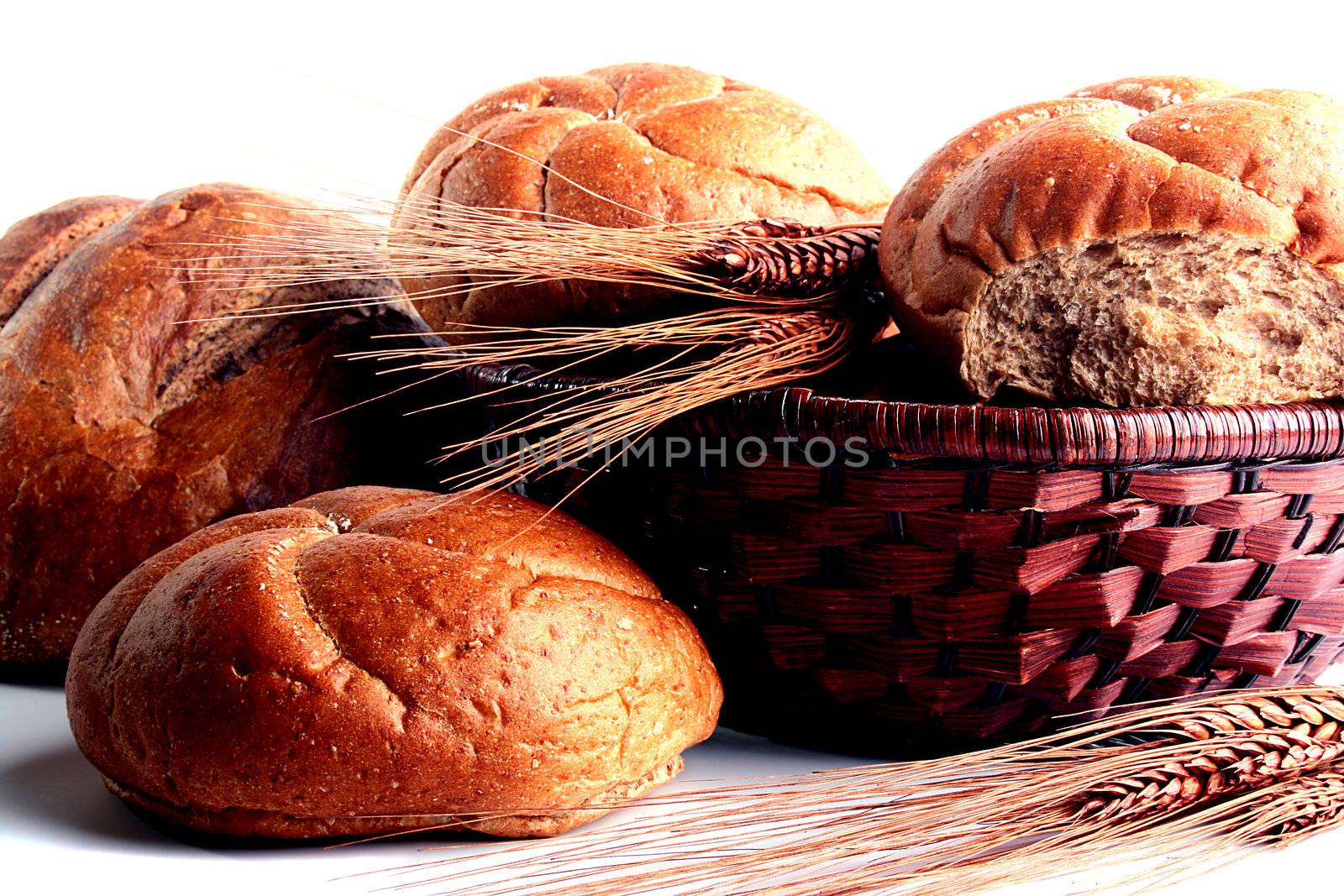 Round bread from a flour of a rough grinding and ears on a white background.