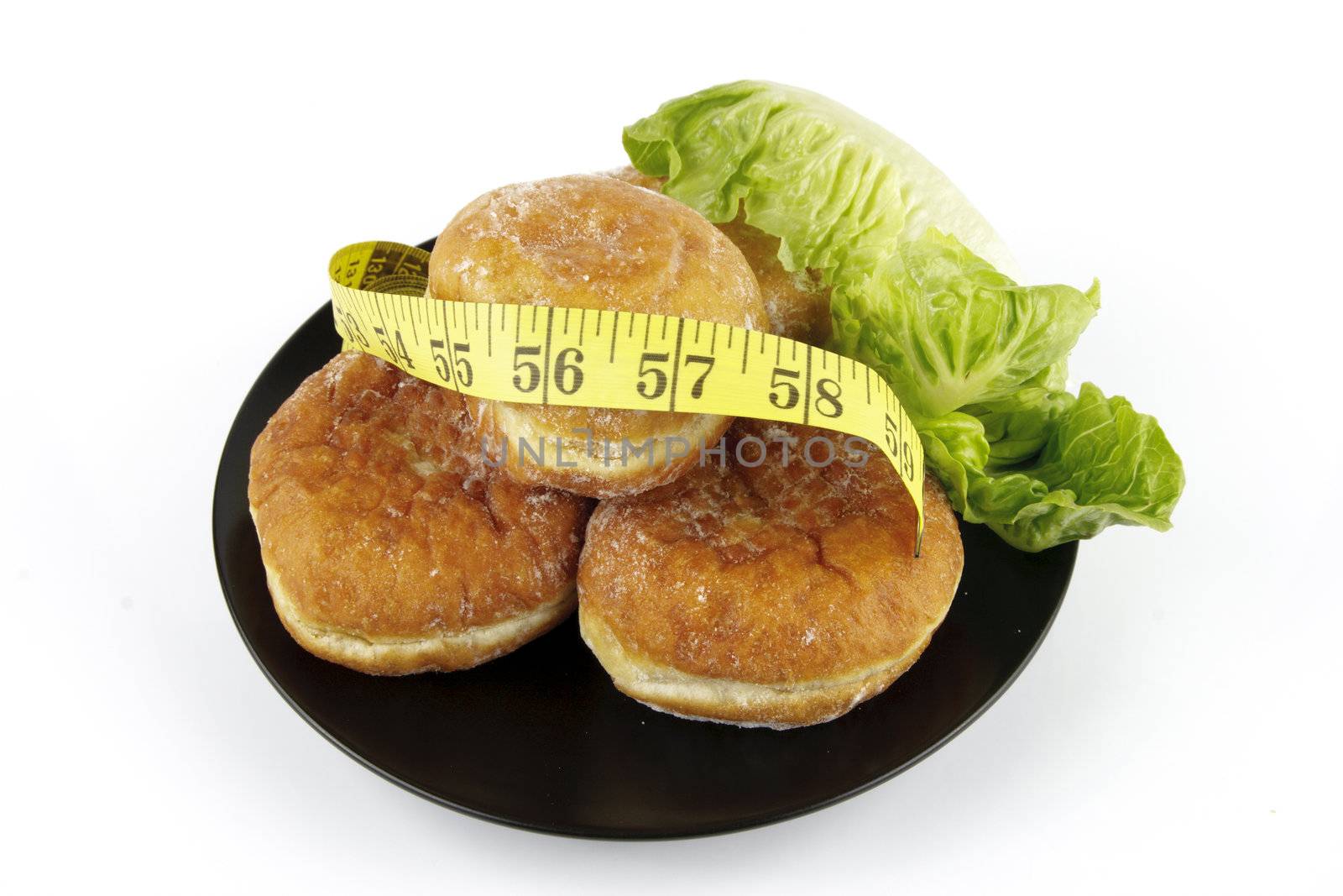 Contradiction between healthy food and junk food using doughnuts and lettace with a tape measure on a reflective white background 