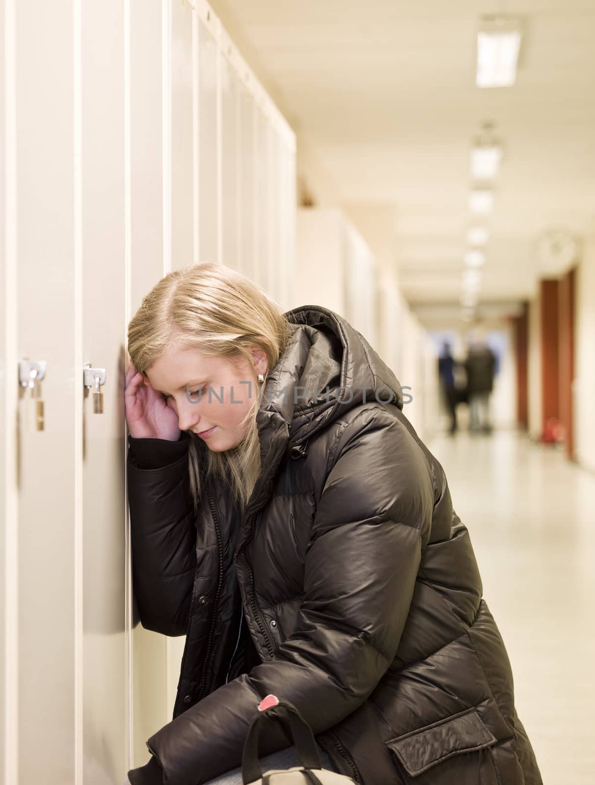 Depressed young woman by the lockers at school