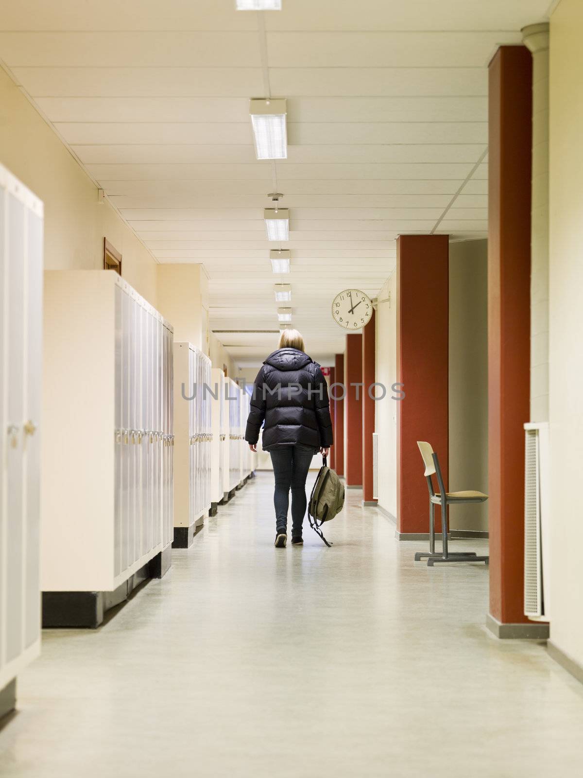 Young woman walking away through a corridor at school