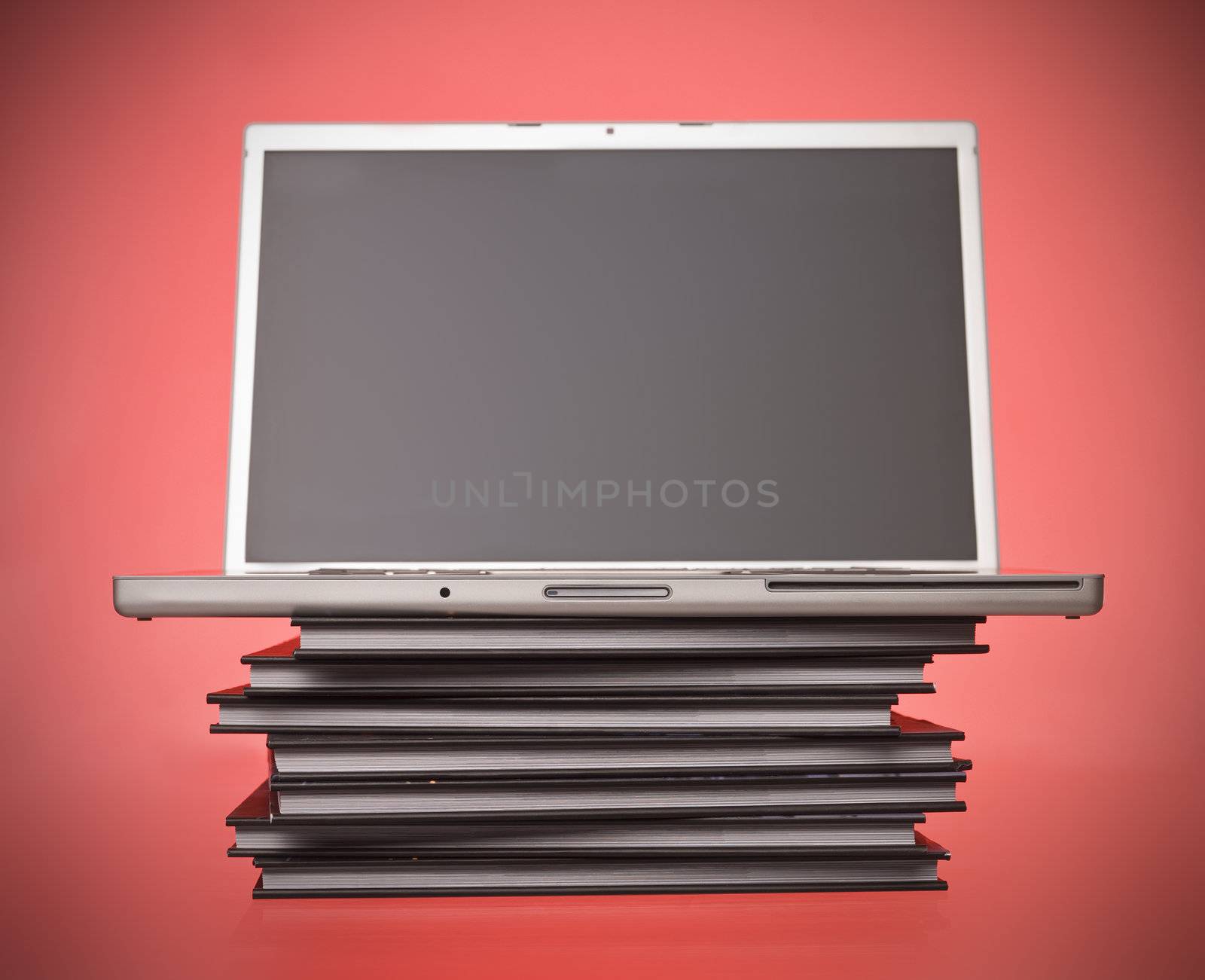 Laptop on top of books by gemenacom
