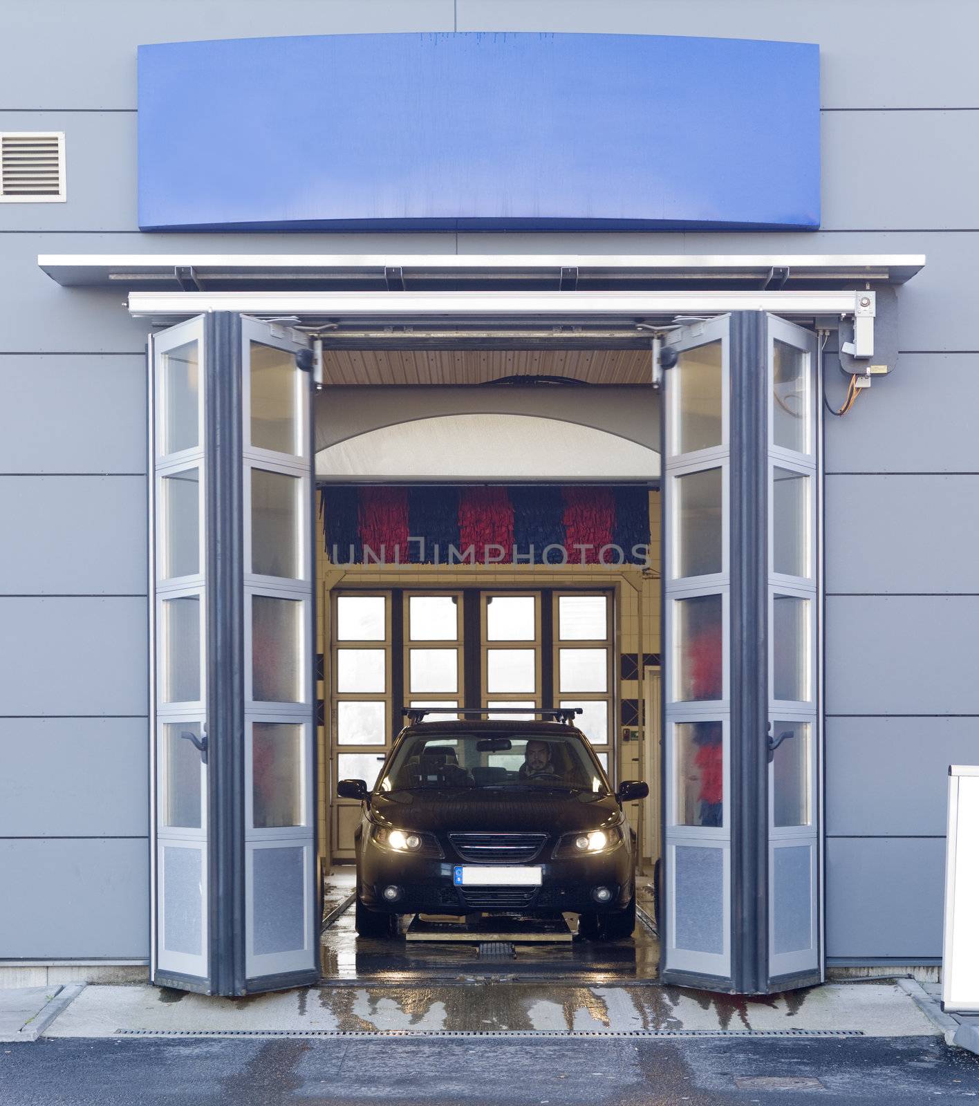 Black car with a male driver washing the car in a car wash