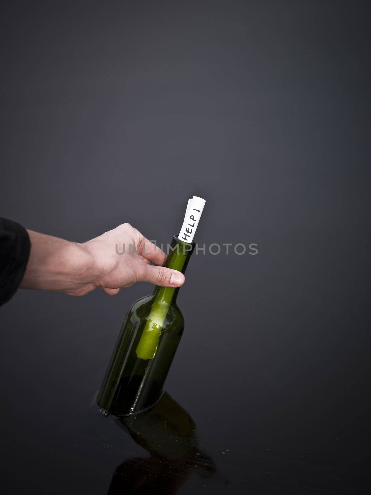 Hand picking up a bottle with a message in it.